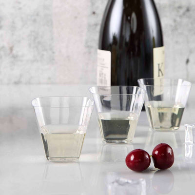 Transparent wine glasses with white wine and cherries on a marble surface.