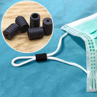 Black silicone ear strap adjusters for masks on a blue background.