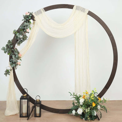 Decorative circular arch with floral accents and lanterns on a wooden floor.