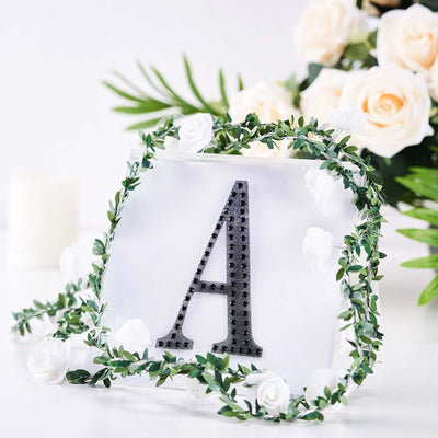 Decorative letter "A" with floral accents and greenery.