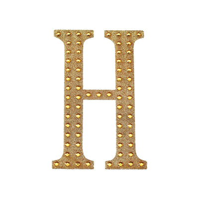 Gold studded letter "H" on a white background.