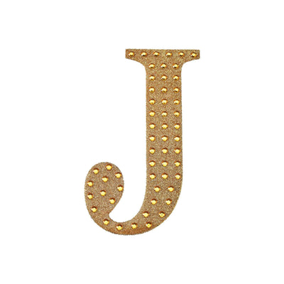 Gold studded letter J on a plain background