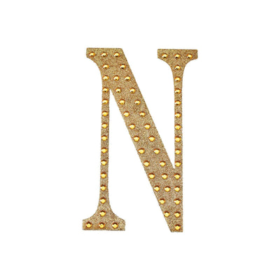 Gold studded letter "N" on a white background.