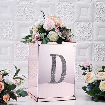 Decorative floral box with rhinestone "D" against a textured white background.