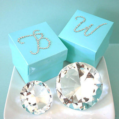 Turquoise gift boxes with decorative letters and crystal diamonds on a plate.
