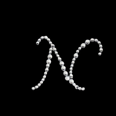 Silver bead letter "N" art piece on black background.
