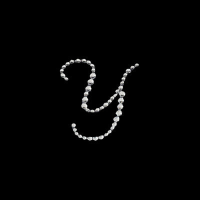 Silver beaded letter "Y" design on a black background.