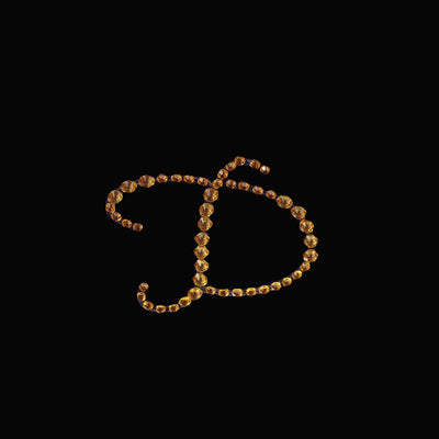"Stylized letter D made of amber gemstones on a black background"