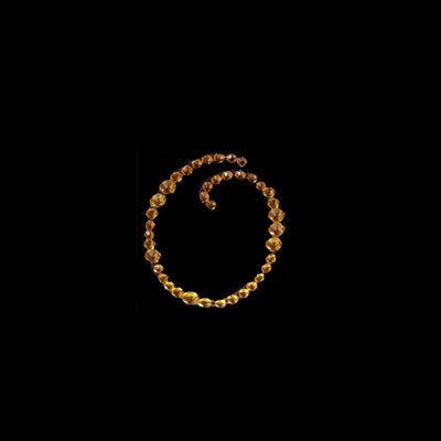 Gold beaded necklace in a spiral design on a black background.