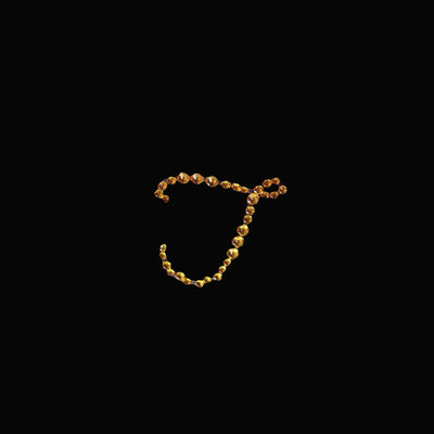 Golden letter "J" made of beads on a black background.