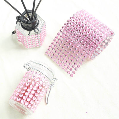 Pink decorative items with rhinestones, including a jar and ribbon.