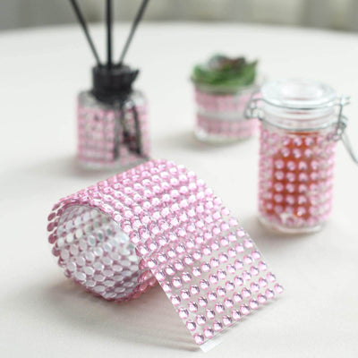 Pink rhinestone ribbon roll with decorative glass jars on a table.