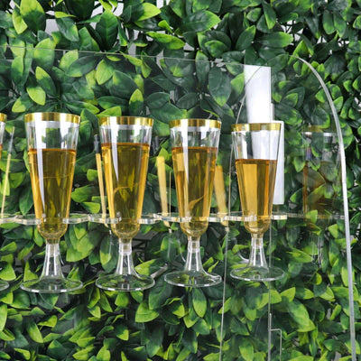 Four elegant glasses filled with golden liquid displayed against a leafy backdrop.