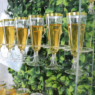 Elegant champagne glasses with golden rims filled with drink against a green backdrop.