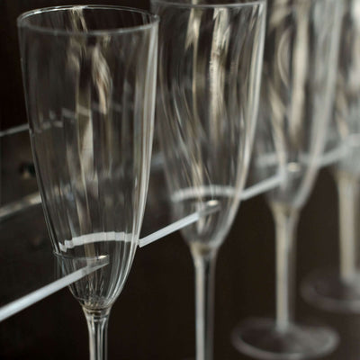 Elegant clear champagne flutes lined up on a shelf.