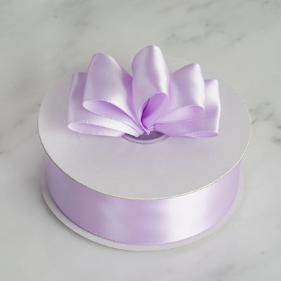 Purple satin ribbon with a bow on a white spool.
