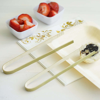 Elegant golden tongs beside a dessert and fresh strawberries.