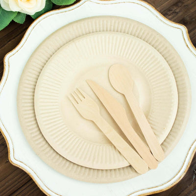 Eco-friendly disposable plates and cutlery set on rustic wooden background.