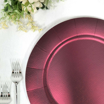 Burgundy textured disposable plate on a table with cutlery and floral accents.