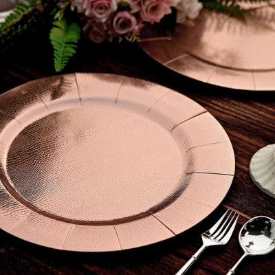 Rose gold textured charger plates on a rustic wooden table setting.
