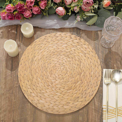 Woven natural placemat on a wooden table with candles and flowers.