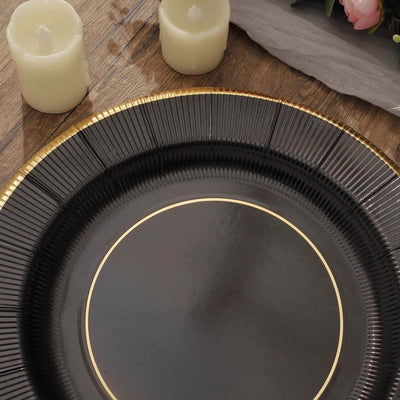 Black decorative platter with gold trim on a wooden table.