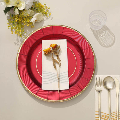 Red decorative plate with floral napkin and cutlery on a neutral table setting.