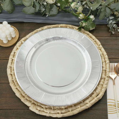 Silver charger plate on a woven placemat with greenery backdrop.