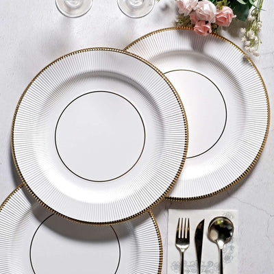 Elegant white plates with gold accents arranged on a table setting.