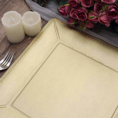 Gold textured serving platter on a rustic wooden table with candles and flowers.