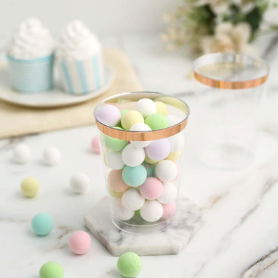 Clear cup filled with pastel colored balls on a marble surface.