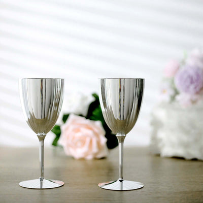 Silver wine glasses on a wooden table with flowers in the background.
