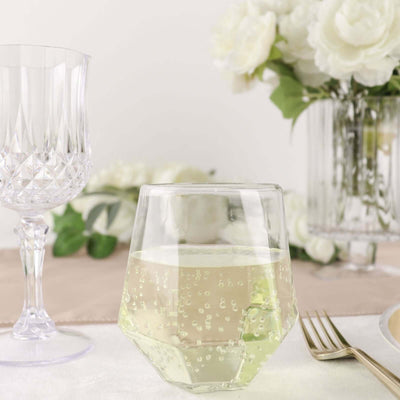 Clear geometric glass with sparkling beverage on a table setting.