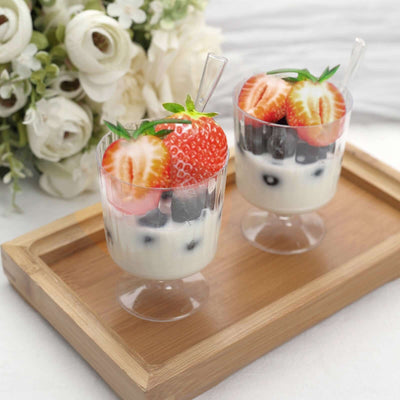 Dessert cups with yogurt, blueberries, and strawberries on a wooden tray.