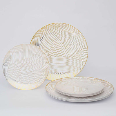 Elegant white plates with gold line patterns, set against a plain backdrop.