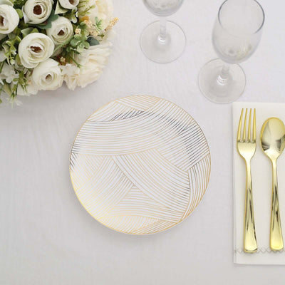 Elegant gold and white patterned dinner plate with cutlery and glasses