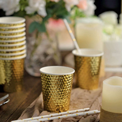 Gold sequin party cups with straws on a festive table setting.