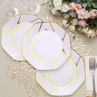 Elegant white plates with gold geometric design, arranged with floral centerpiece.