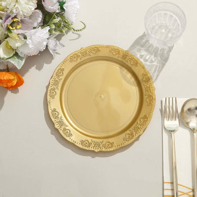 Gold decorative plate on a table with utensils and flowers.