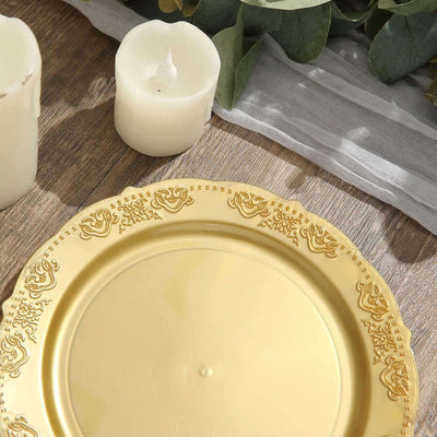 Gold decorative plate on rustic wooden table with candles and greenery.