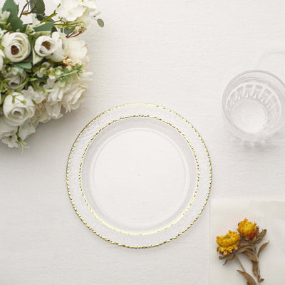 Clear decorative plate with gold rim surrounded by flowers and a glass