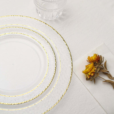 Elegant glass plates with gold trim and dried flowers on a textured surface.