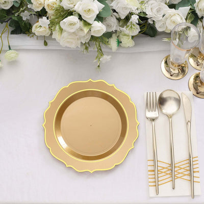 Gold scalloped charger plate with silver cutlery and elegant floral decor.
