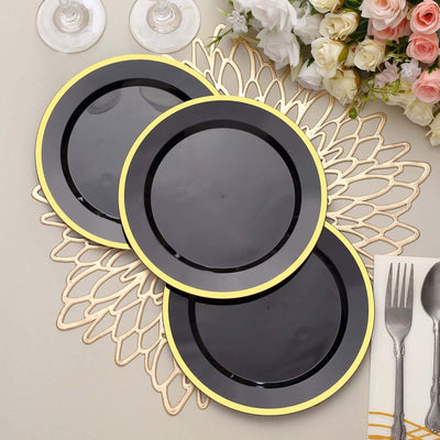 Set of three black plates with gold rims on a lace placemat.