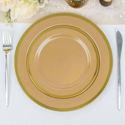 Gold rimmed dinner plates set on a table with silver cutlery.