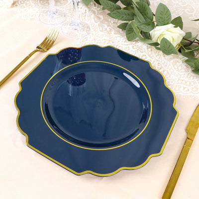 Navy blue scalloped dinner plate with gold trim on a table setting.