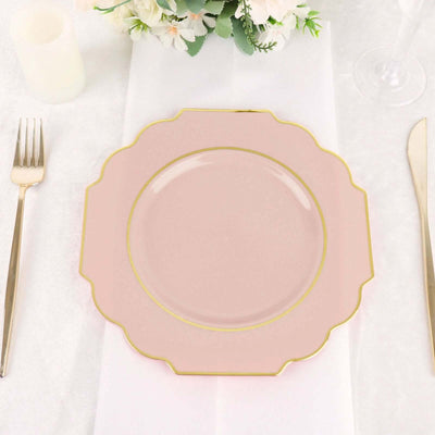 Pink scalloped plate with gold trim on a table setting.