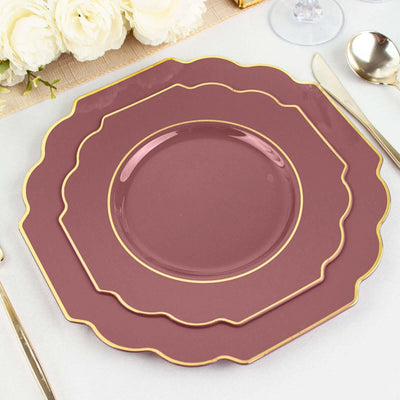 Elegant burgundy plates with gold trim stacked on a table setting.