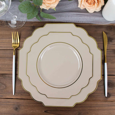 Elegant beige dinner plate set with gold trim and white-handled cutlery on a wooden table.