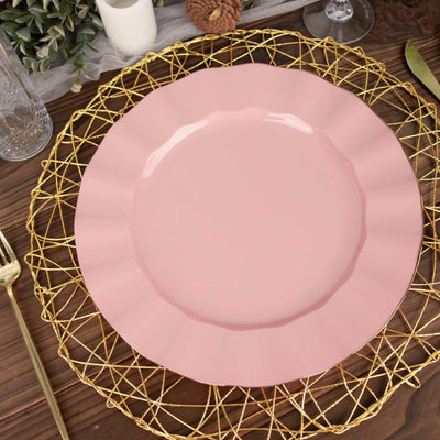 Pink scalloped plate on a gold wire charger against a wooden table.